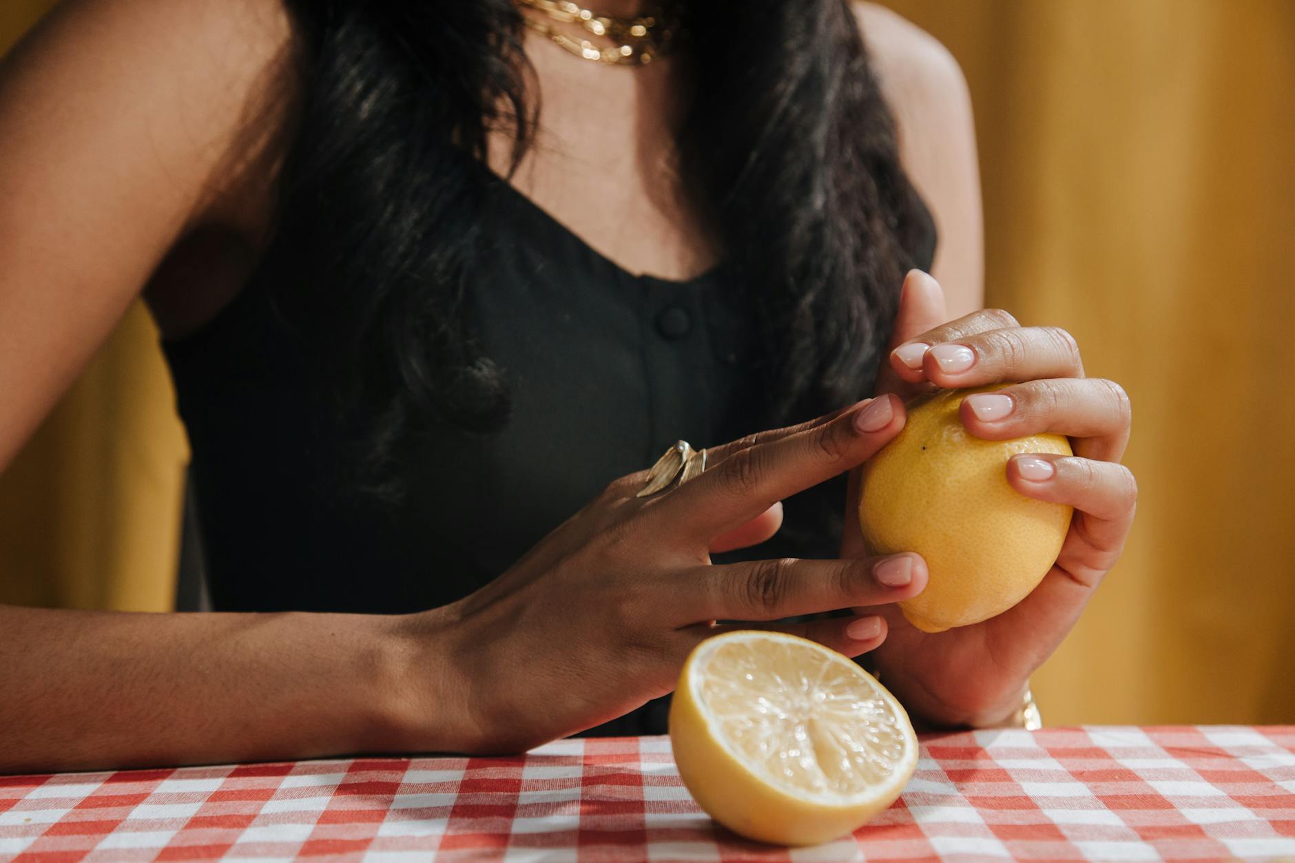 Two hands holding pink and blue silicone vibrators against a pastel background