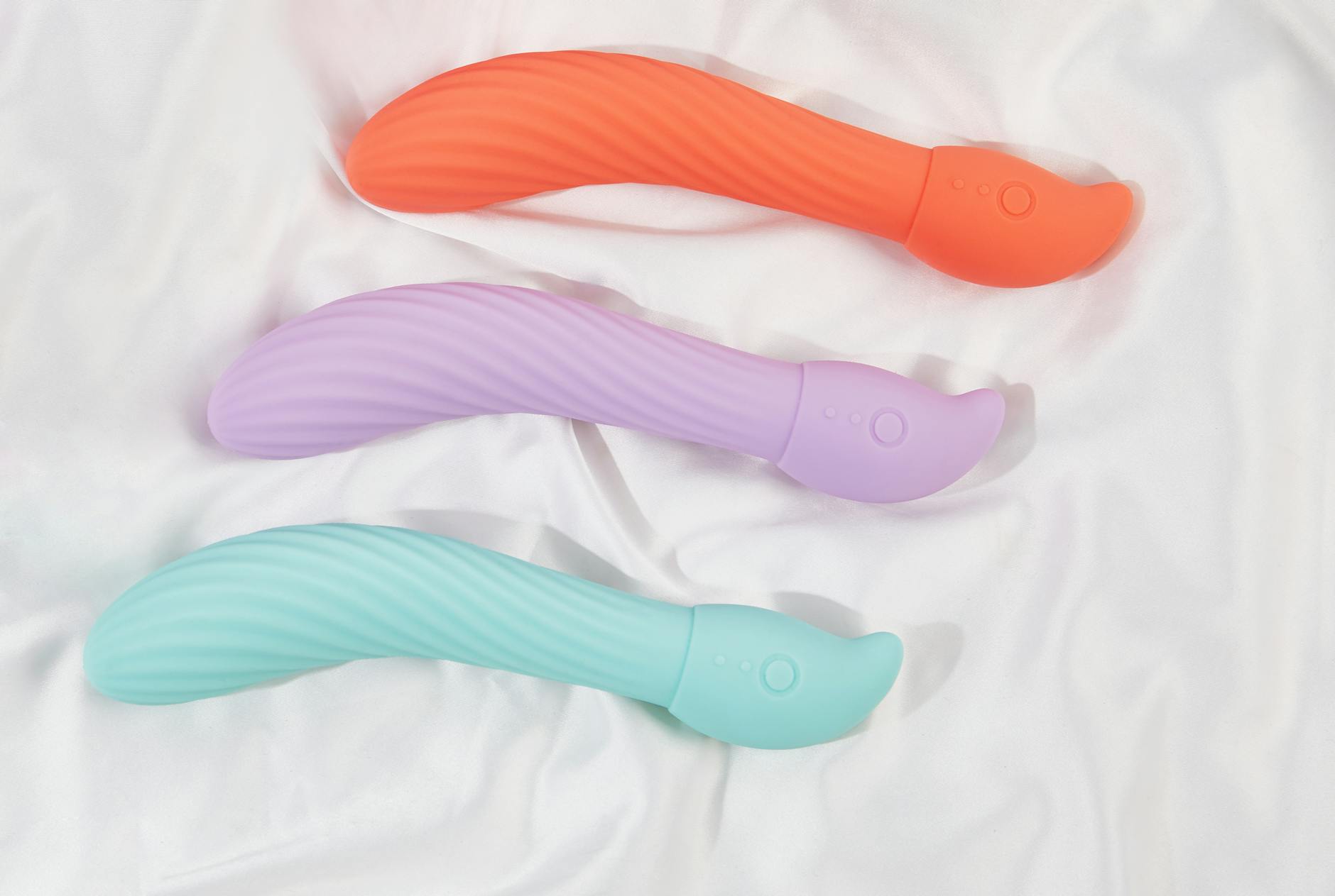 Three colorful lemon vibrators and clitoral toys arranged on white fabric