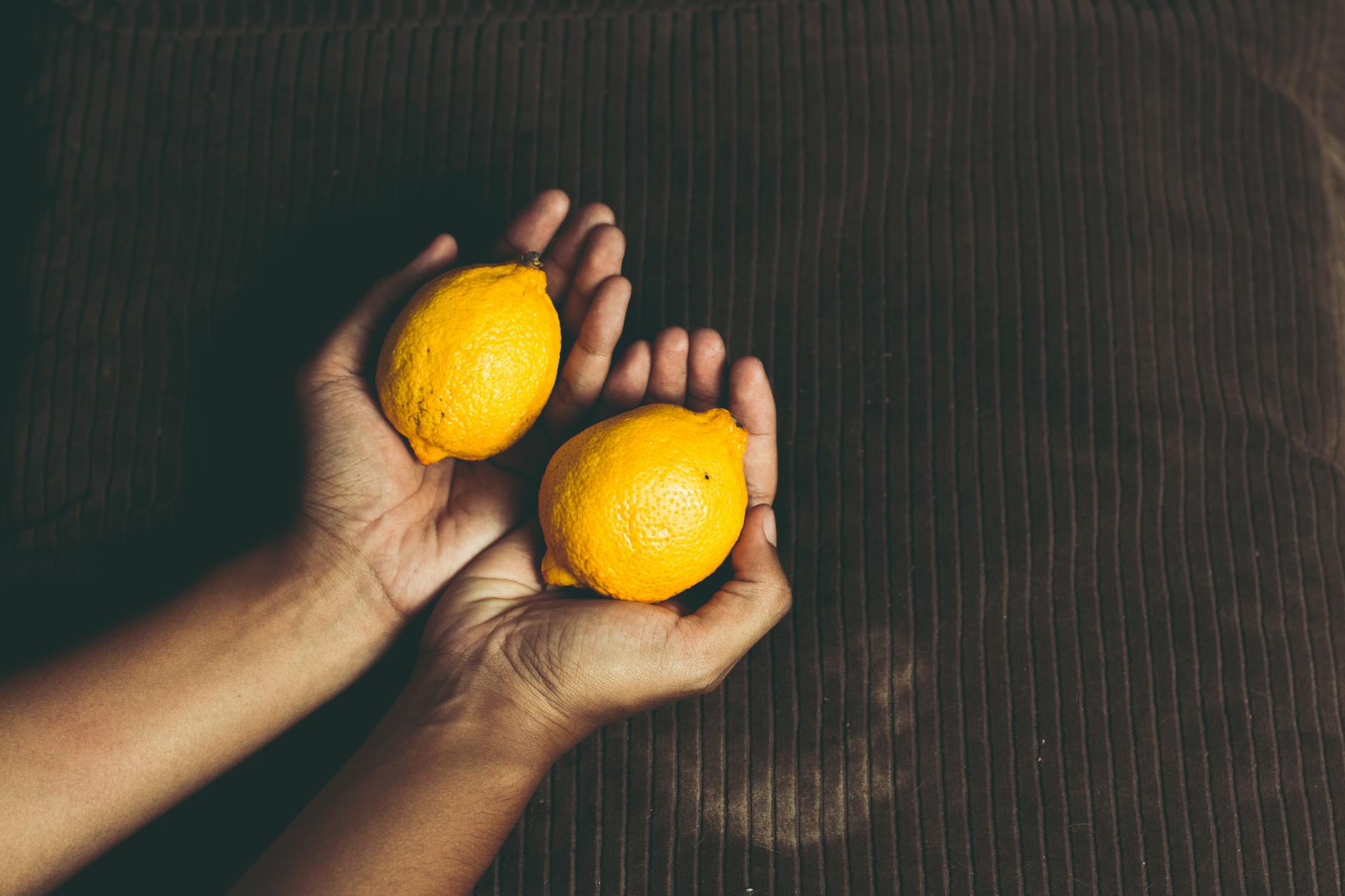 Close-up of fresh lemons held in cupped hands, symbolizing grounding and presence
