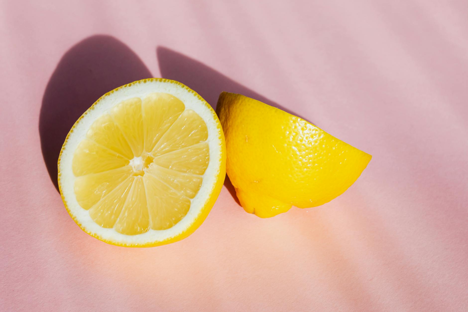 Fresh lemon halves on a pink background, symbolizing freshness and natural lubrication