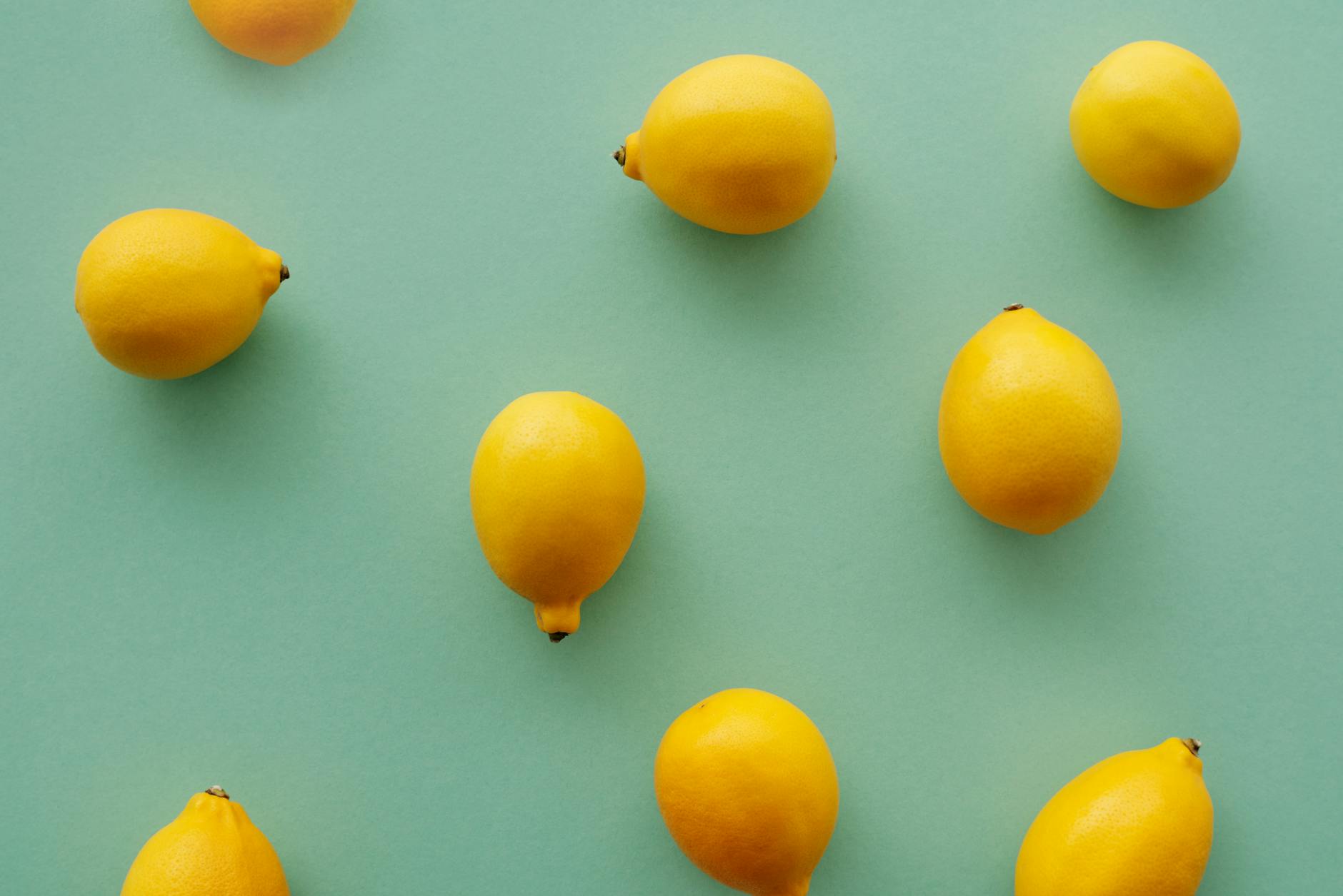 Bright yellow lemons arranged on a pastel green background, symbolizing fresh sensation and renewal