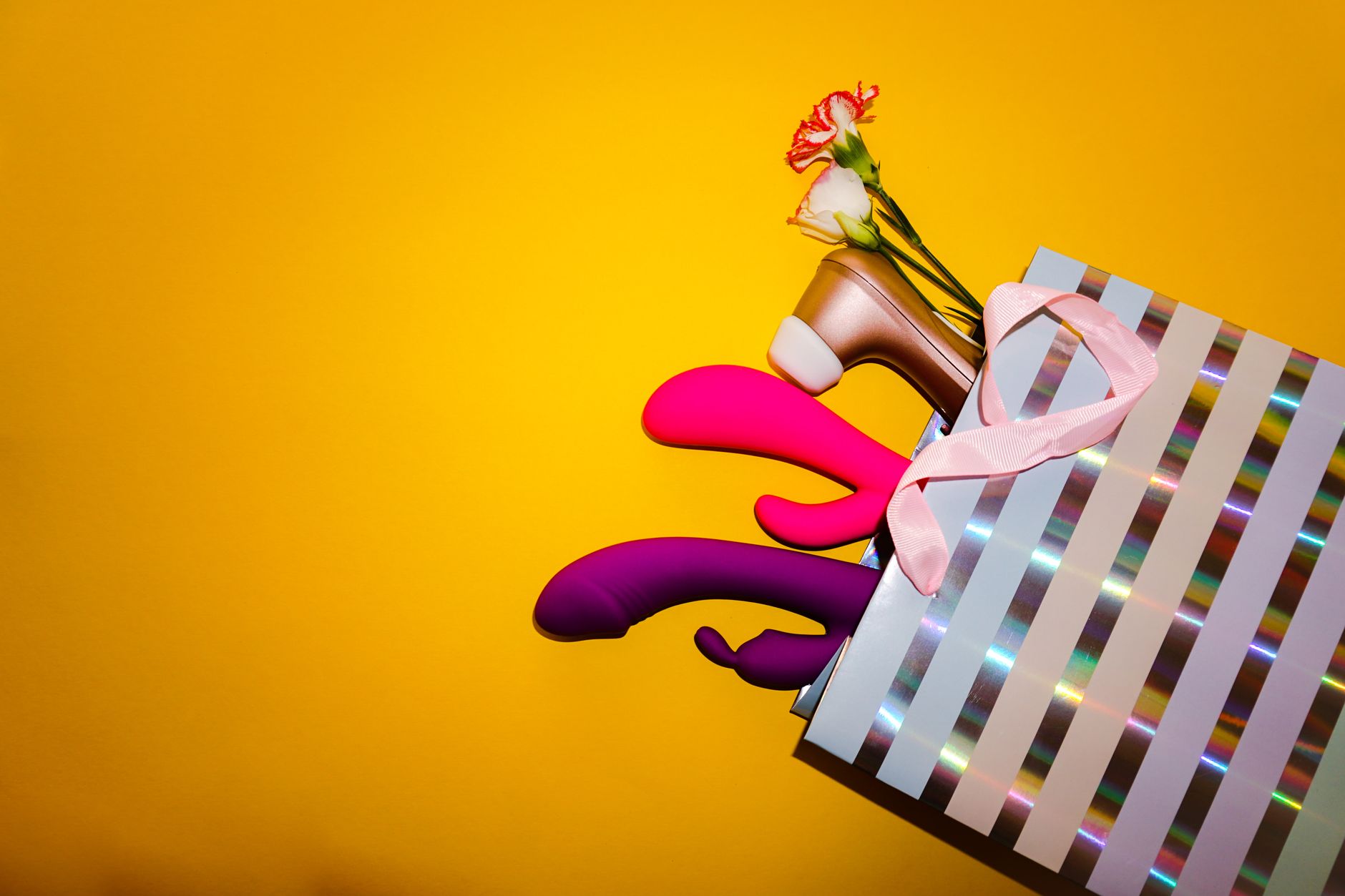 Pink vibrator surrounded by heart confetti and lit candles on a purple surface, symbolizing intimate self-care and tension release