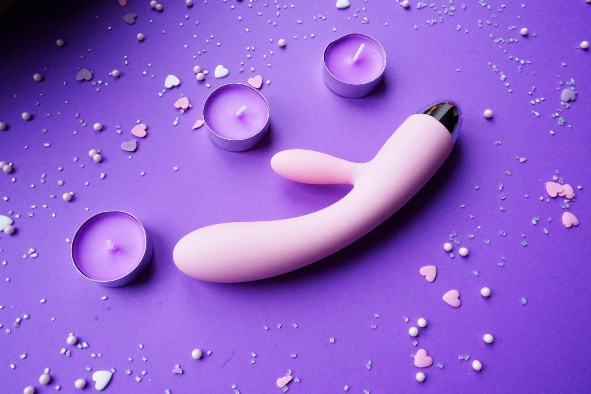 Pink and purple lemon vibrator on a romantic background with candles and confetti