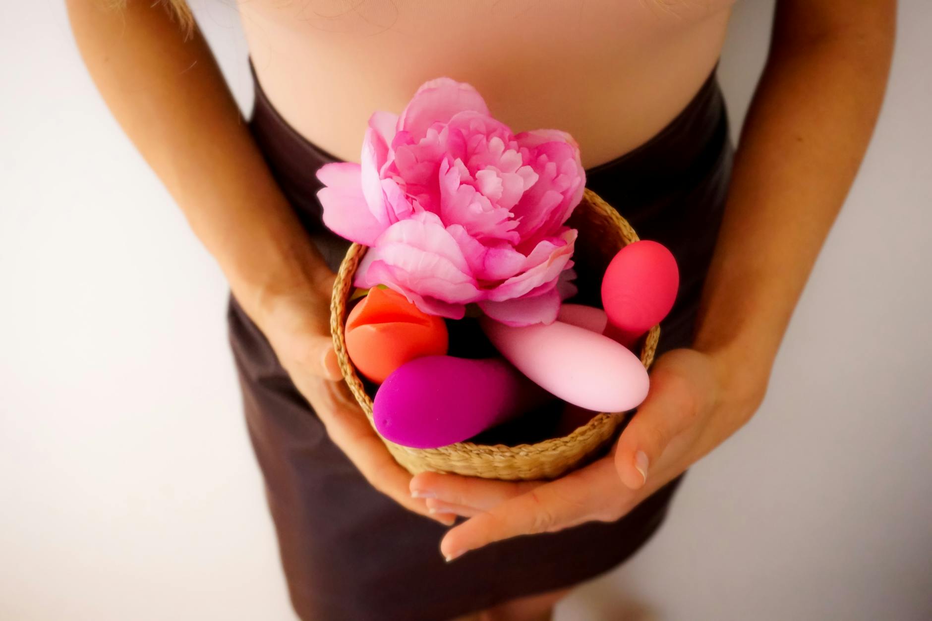 Woman holding blue and pink silicone vibrators with a contemplative expression